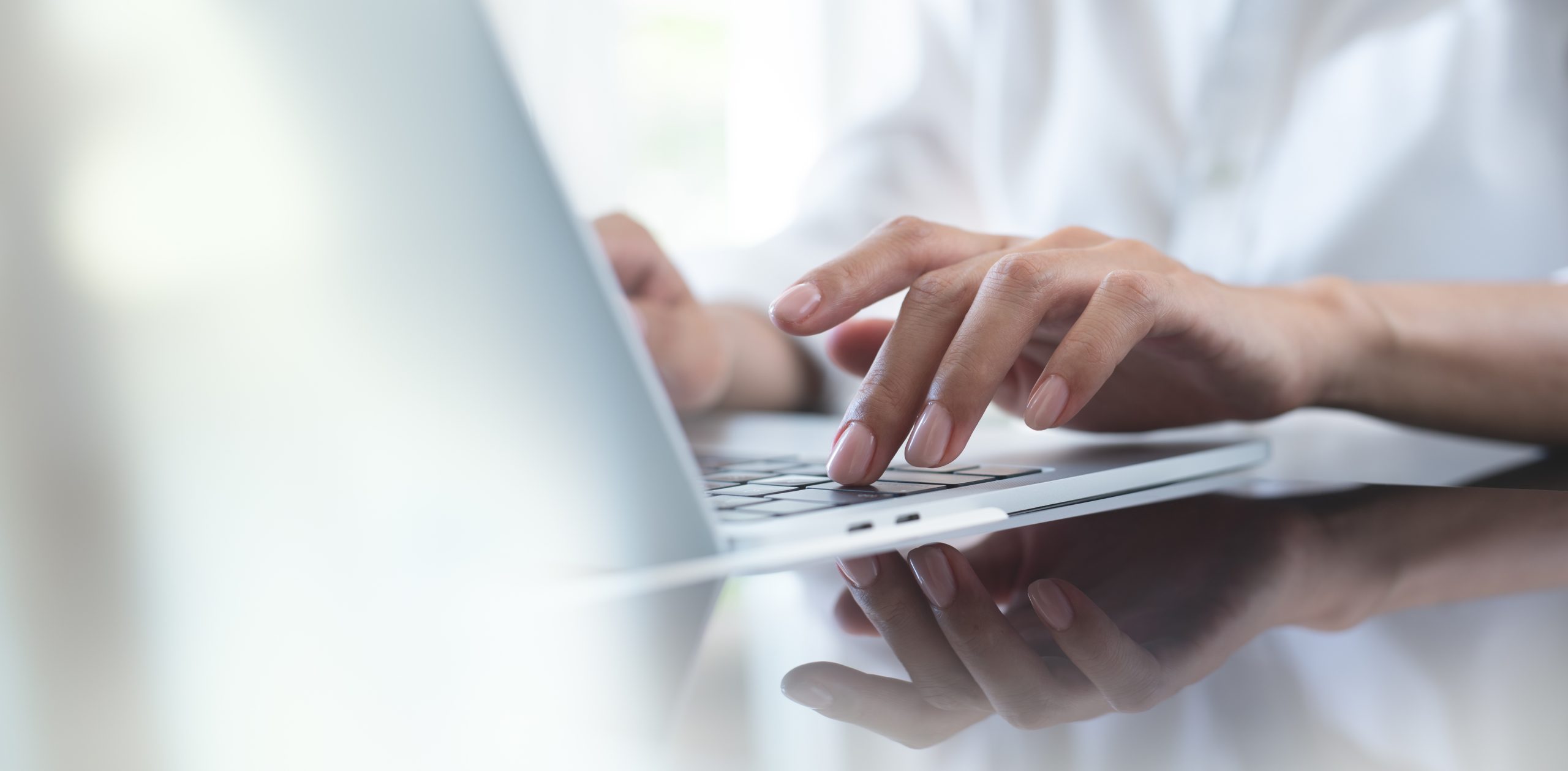 close-up-of-business-woman-hand-typing-on-laptop-computer-keyboard-with-reflection-on-digital-tablet-on-office-table-online-working-surfing-the-internet-distant-job-remote-work-concept